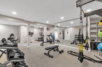 A gym with weights and cardio equipment in a room with white walls